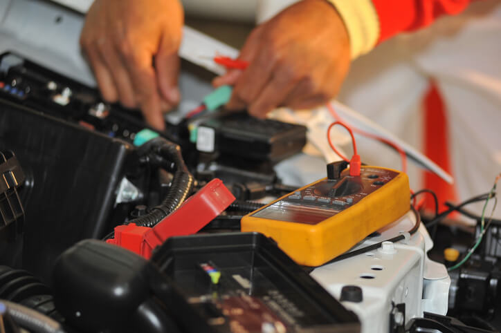 Automotive student diagnosing a low-voltage system issue in a workshop