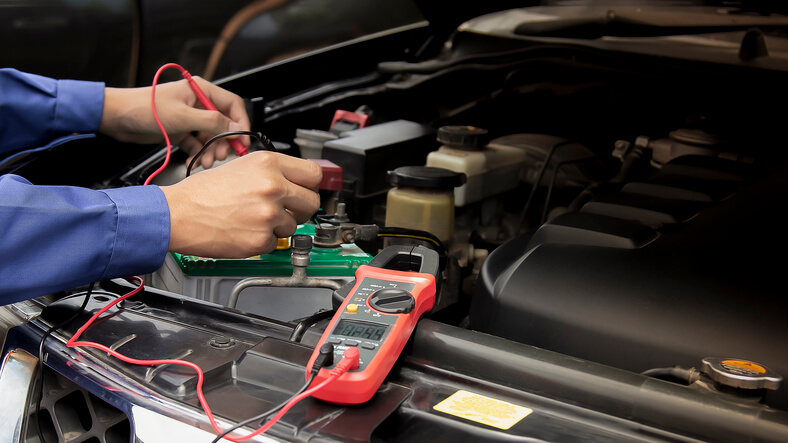 An automotive student learning to diagnose bad alternator symptoms in training workshop