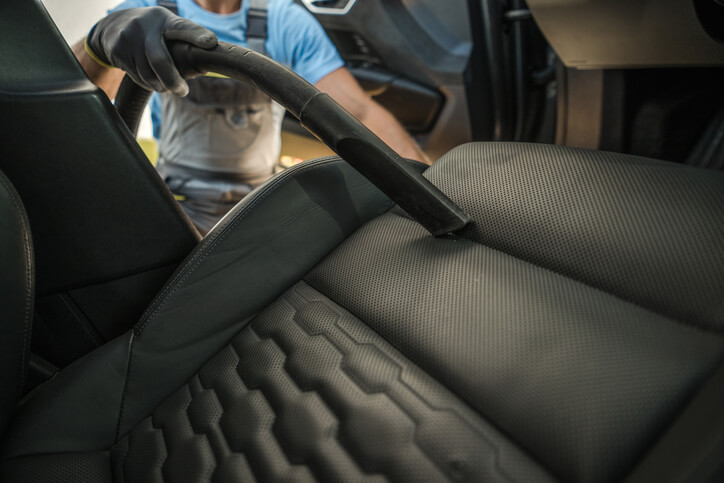 An interior car detailing service showing vacuuming and upholstery cleaning