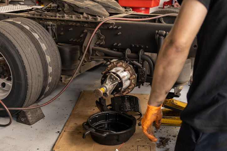 Technician draining rear differential fluid during maintenance service