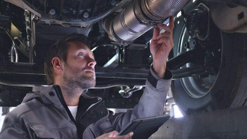 A technician is inspecting exhaust emissions and catalytic converter performance using diagnostic equipment