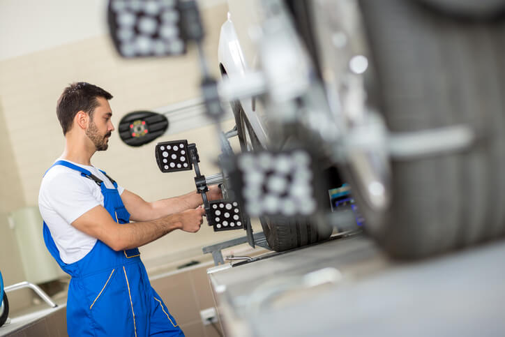 An automotive student learning wheel alignments during hands-on training in a shop