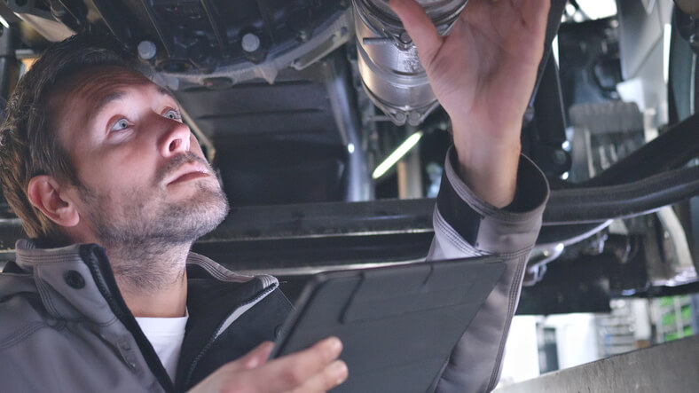 A technician performing exhaust system diagnostics to identify a catalytic converter restriction