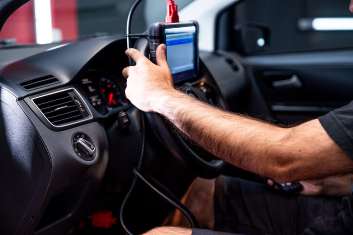 A mechanic using an OBD2 scanner to diagnose catalytic converter symptoms and engine performance
