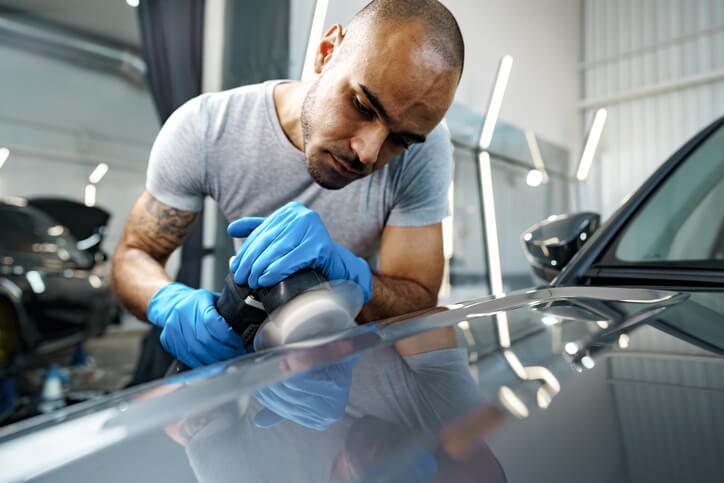 A detailer polishing car paint to remove hard water spots
