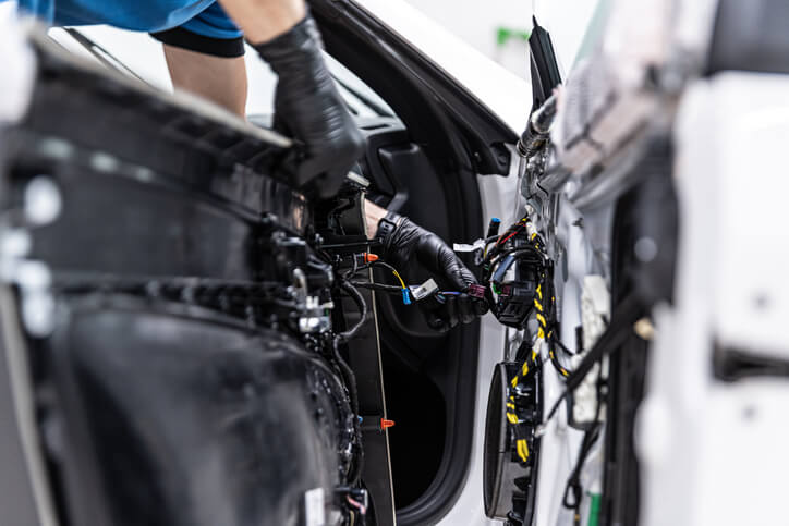 An EV technician is inspecting wiring insulation