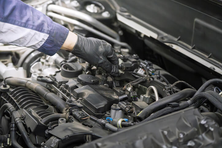 A mechanic wearing protective gloves while testing electrical components