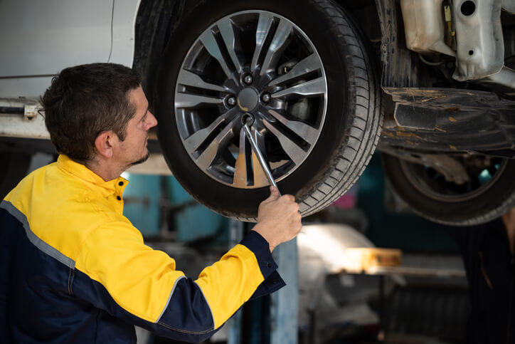 A mechanic rotating a vehicle wheel to check for wheel bearing noise and resistance