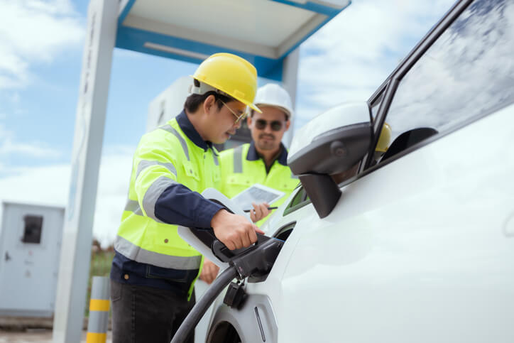 A technician testing DC fast charging communication on an electric vehicle