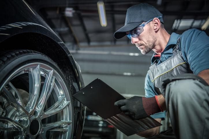 Mechanic performing tire and brake inspections on an electric vehicle