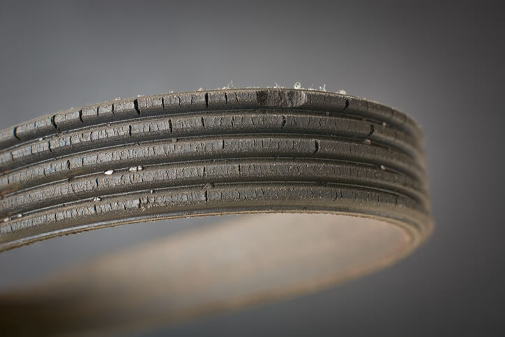 A close-up of a worn serpentine belt showing visible cracking and glazing.