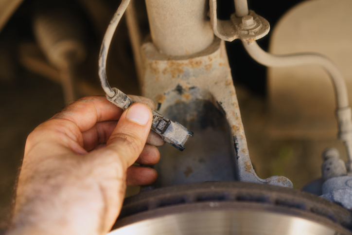 A mechanic is inspecting the wheel speed sensor during brake system inspection