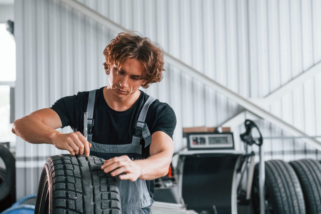 Automotive technician inspecting EV tire wear patterns during service