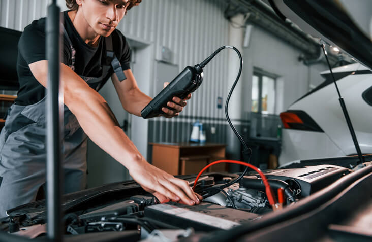 An electric vehicle technician performing diagnostics on an EV in a repair shop