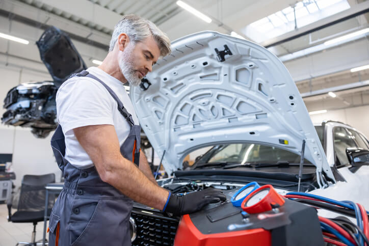 Automotive service technician inspecting an electric vehicle battery cooling system