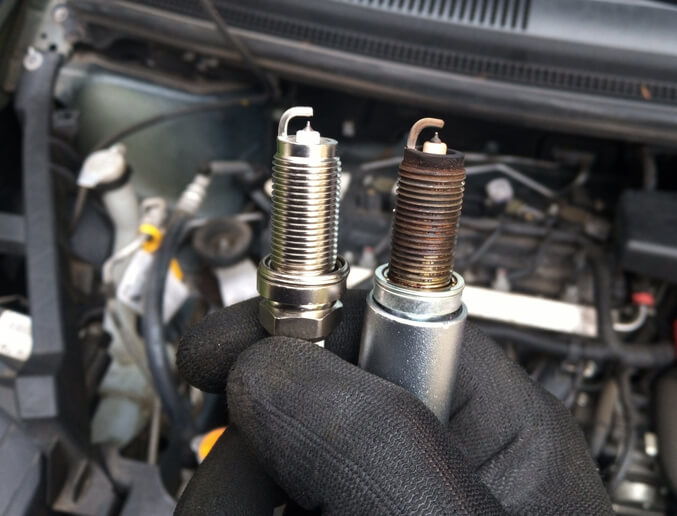 A close-up of worn spark plugs showing electrode wear and deposits