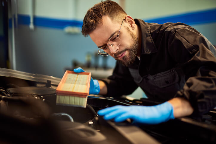 A student in automotive training is learning air filter replacement procedures