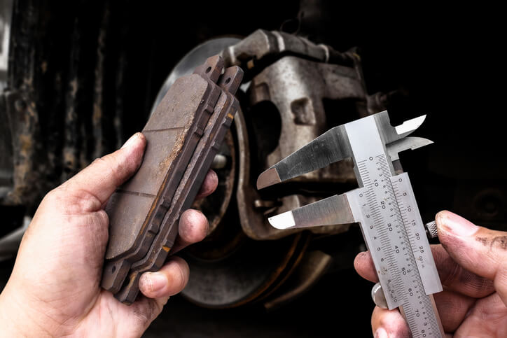 Mechanic measuring brake pad thickness during a vehicle inspection