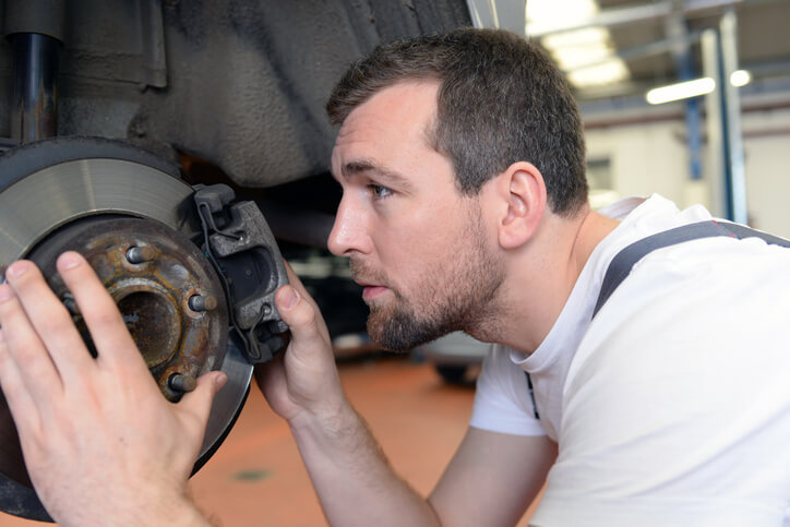 A student learning how to check brake pads during automotive training