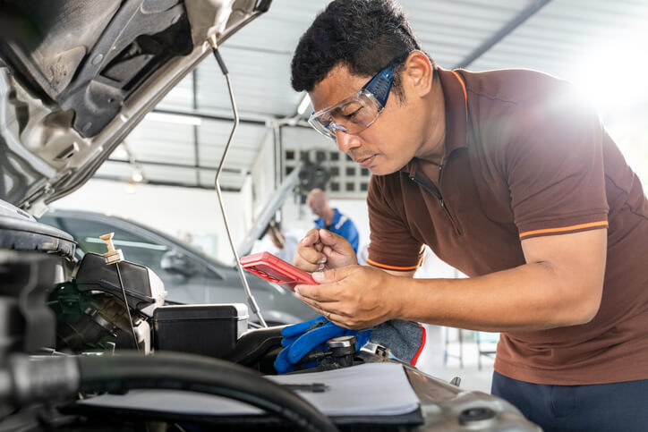 Automotive student reviewing EV battery safety procedures in workshop