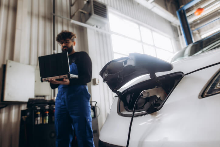 An automotive student using diagnostic equipment to investigate an EV charging complaint