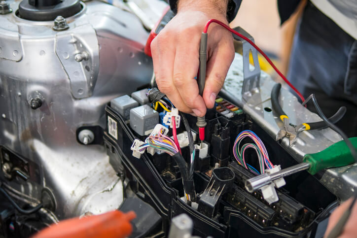 An automotive student testing electrical circuits on a hybrid vehicle