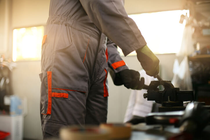 A hybrid and electric vehicle mechanic following high-voltage safety procedures in a workshop