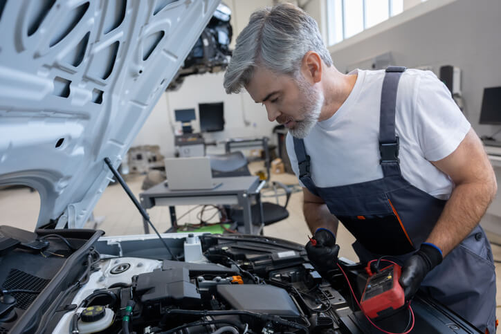 A technician using a digital multimeter to diagnose an electrical fault