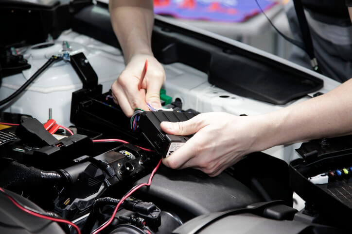 An EV technician is inspecting wiring and electronic control modules during a repair