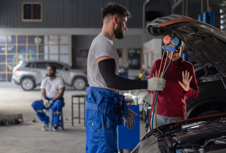 An automotive student learning automotive AC diagnostics in a training shop