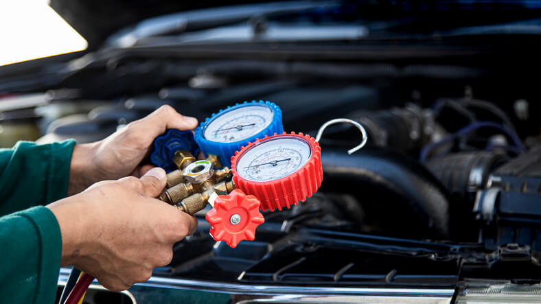 A mechanic testing refrigerant pressures during vehicle air conditioning service