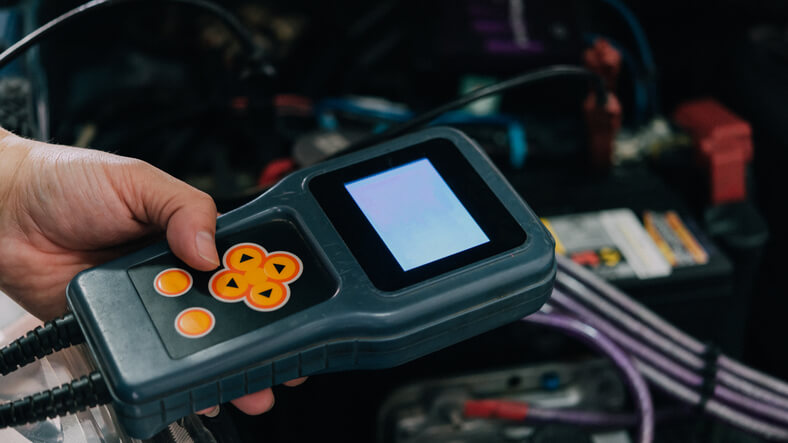 A technician using a scan tool to troubleshoot an EV electrical system