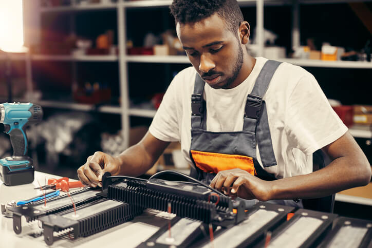 A future hybrid and electric vehicle mechanic inspecting high-voltage wiring and control modules