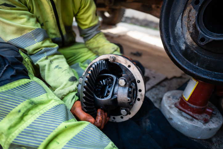 A technician inspecting gears inside a vehicle differential housing