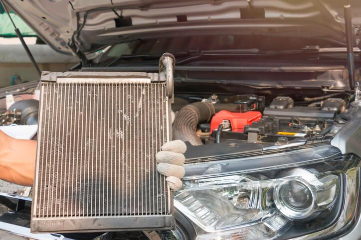 An automotive student is inspecting a car radiator during cooling system training