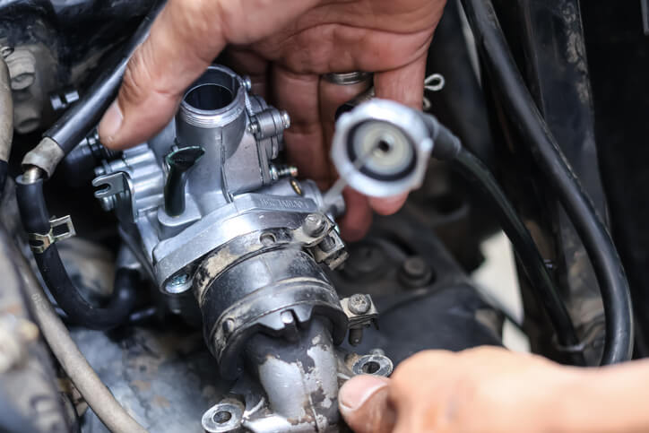 A mechanic adjusting an engine choke during startup on an older car