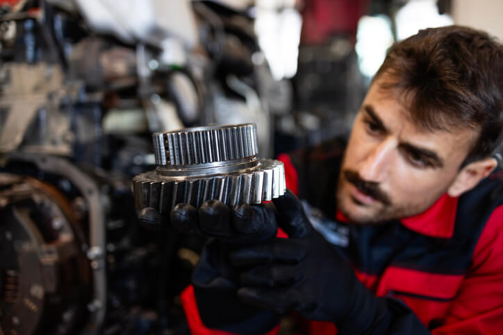 A technician inspecting a transmission and drivetrain assembly in a repair facility