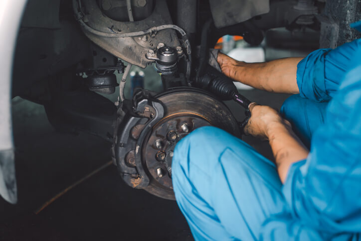A technician examining worn suspension parts during a vehicle inspection