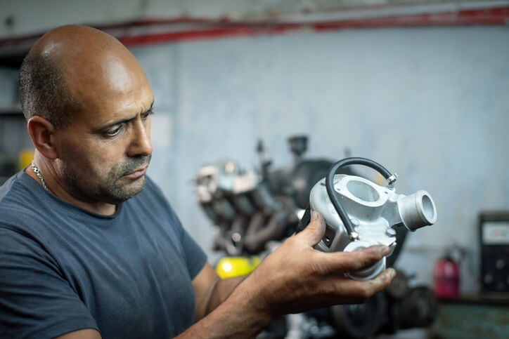 An automotive student examining a turbocharger assembly during hands-on training