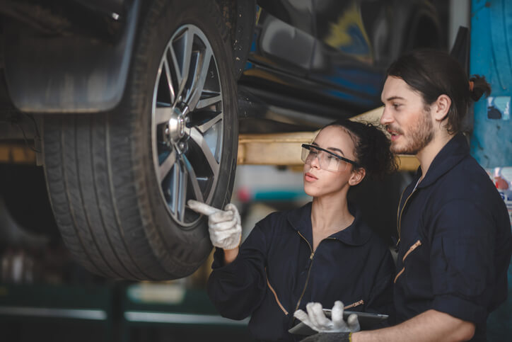 An apprentice automotive technician working alongside a licensed journeyperson mechanic