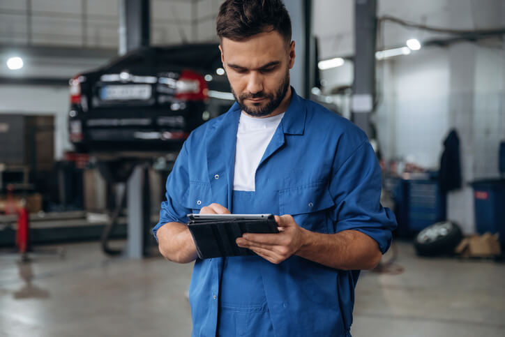 A mechanic reviewing repair orders and labour times in a busy service department