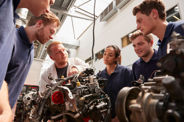 Automotive training students learning fuel and air mixture principles on an older engine