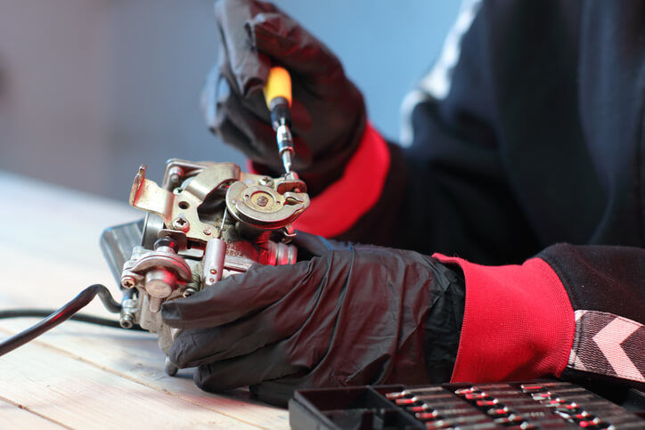A mechanic adjusting a carburetor during engine tuning