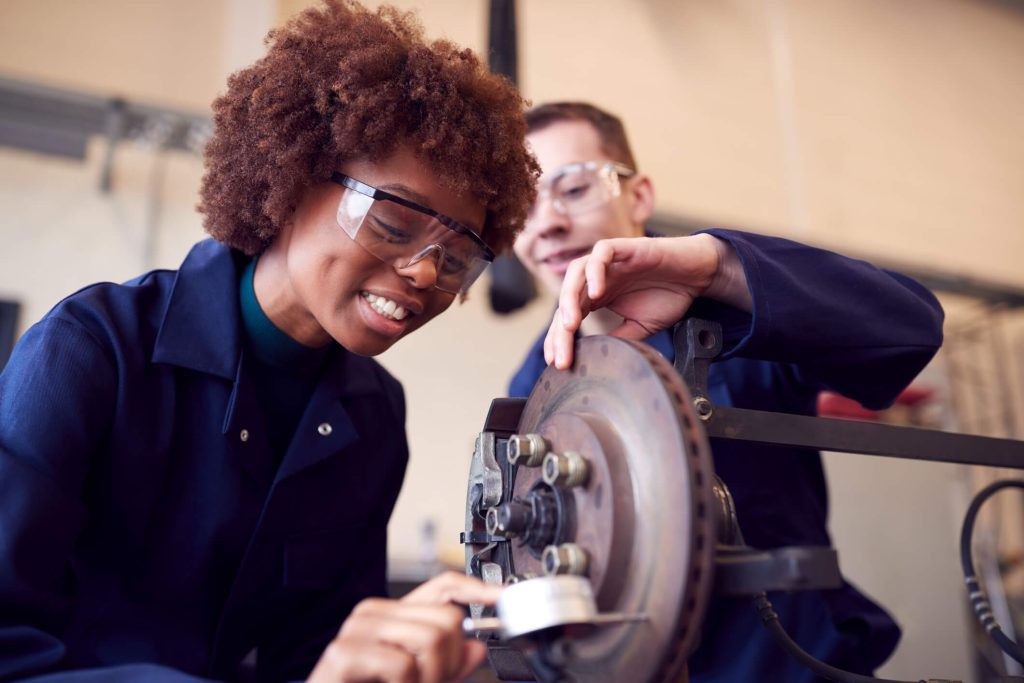 A student learning brake system diagnostics in an automotive training lab