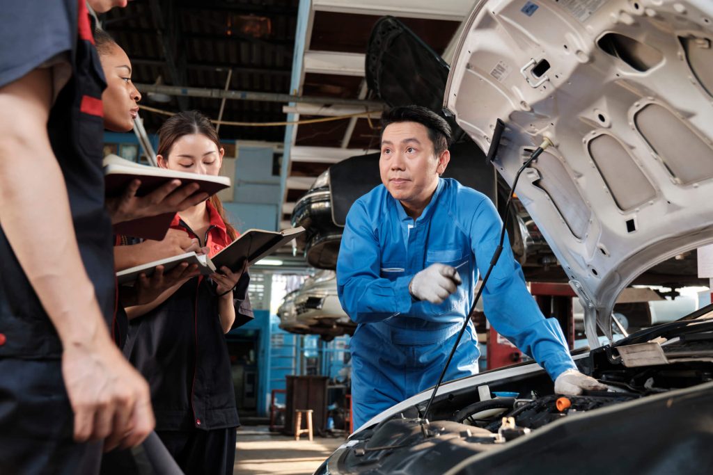 An instructor explaining EV battery safety procedures in an automotive workshop