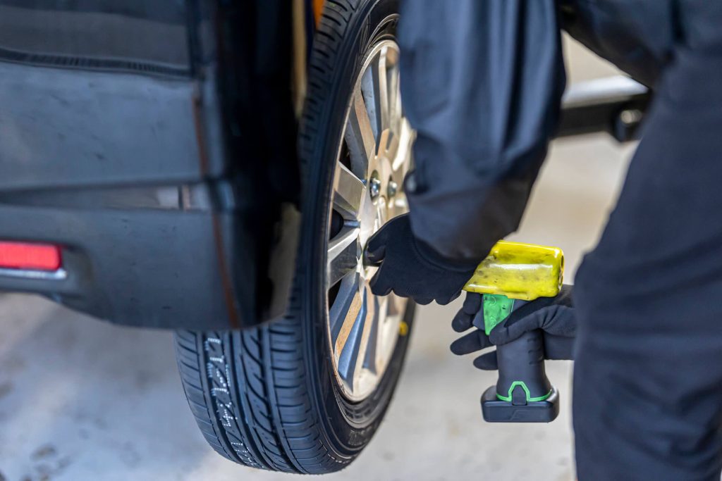 A student performing brake and tire inspection on an electric vehicle