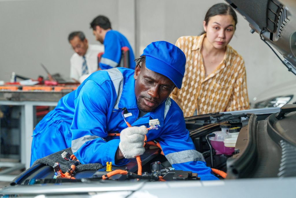 Instructor demonstrating zero-voltage verification on an electric vehicle