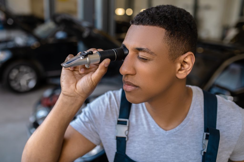 Automotive student testing engine coolant with a refractometer in a Montreal training shop