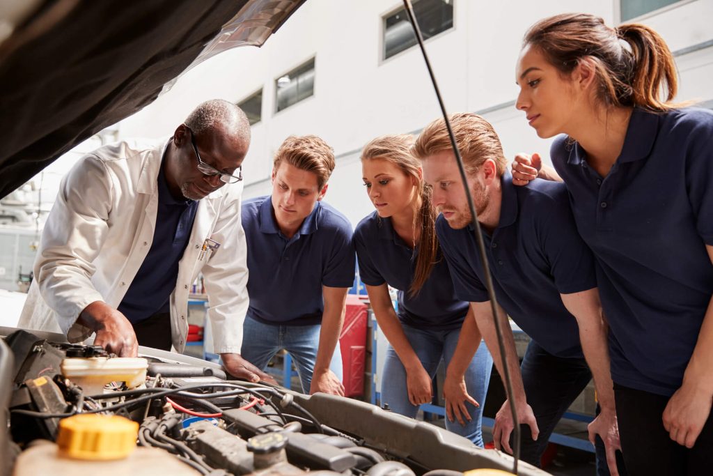 Instructor explaining an electric vehicle battery cooling system to automotive students