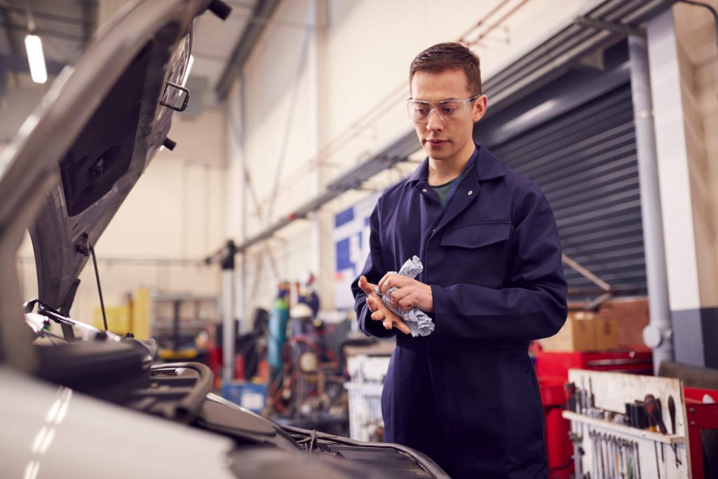 Auto mechanic trainee performing routine maintenance in a training shop
